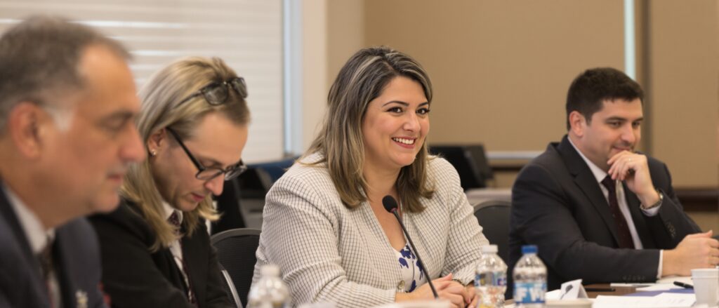 Woman smiling at a dissertation committee meeting with colleagues, discussing research methodologies and feedback.